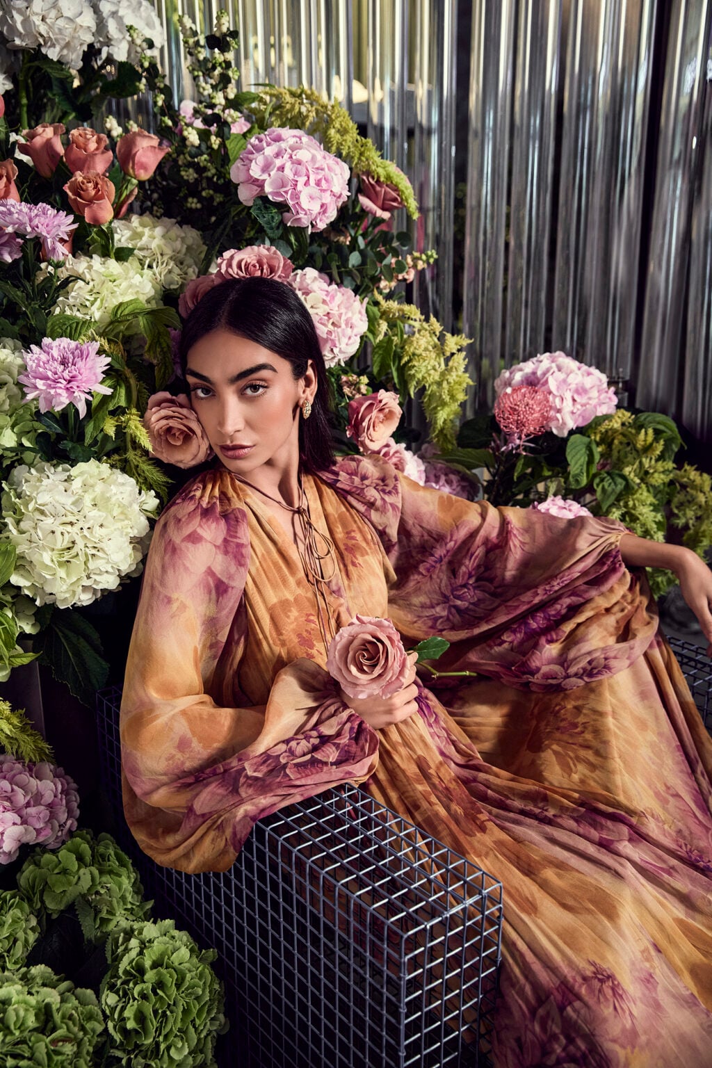 Woman in a floral dress among hydrangeas and roses at a florist