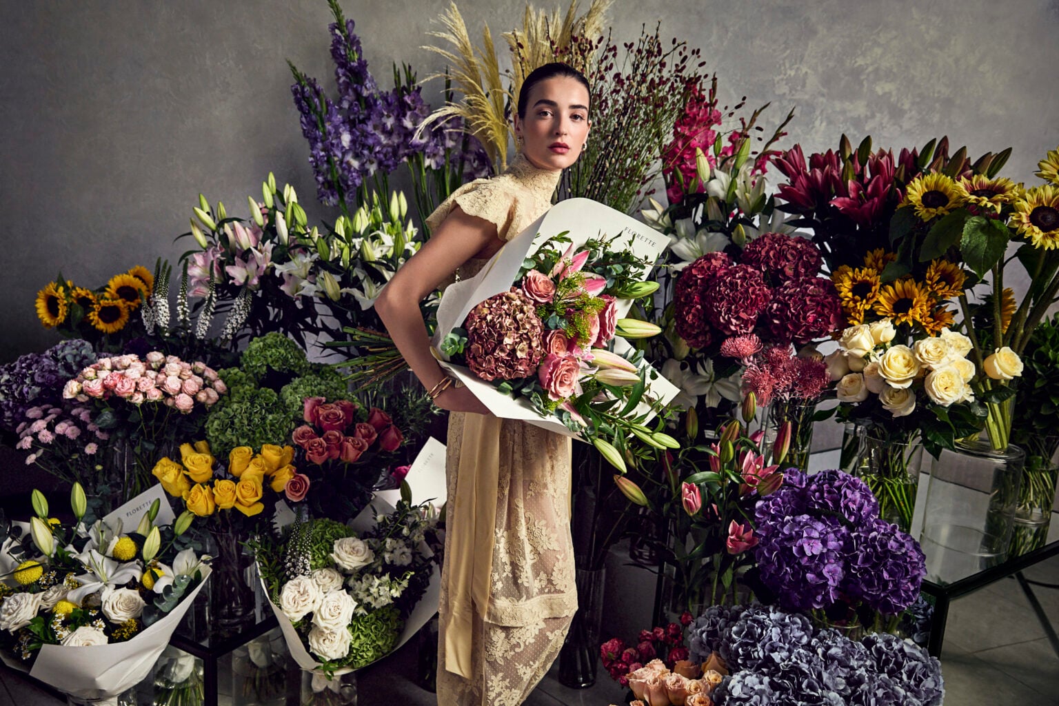 Woman holding a bouquet among buckets of fresh flowers at a florist