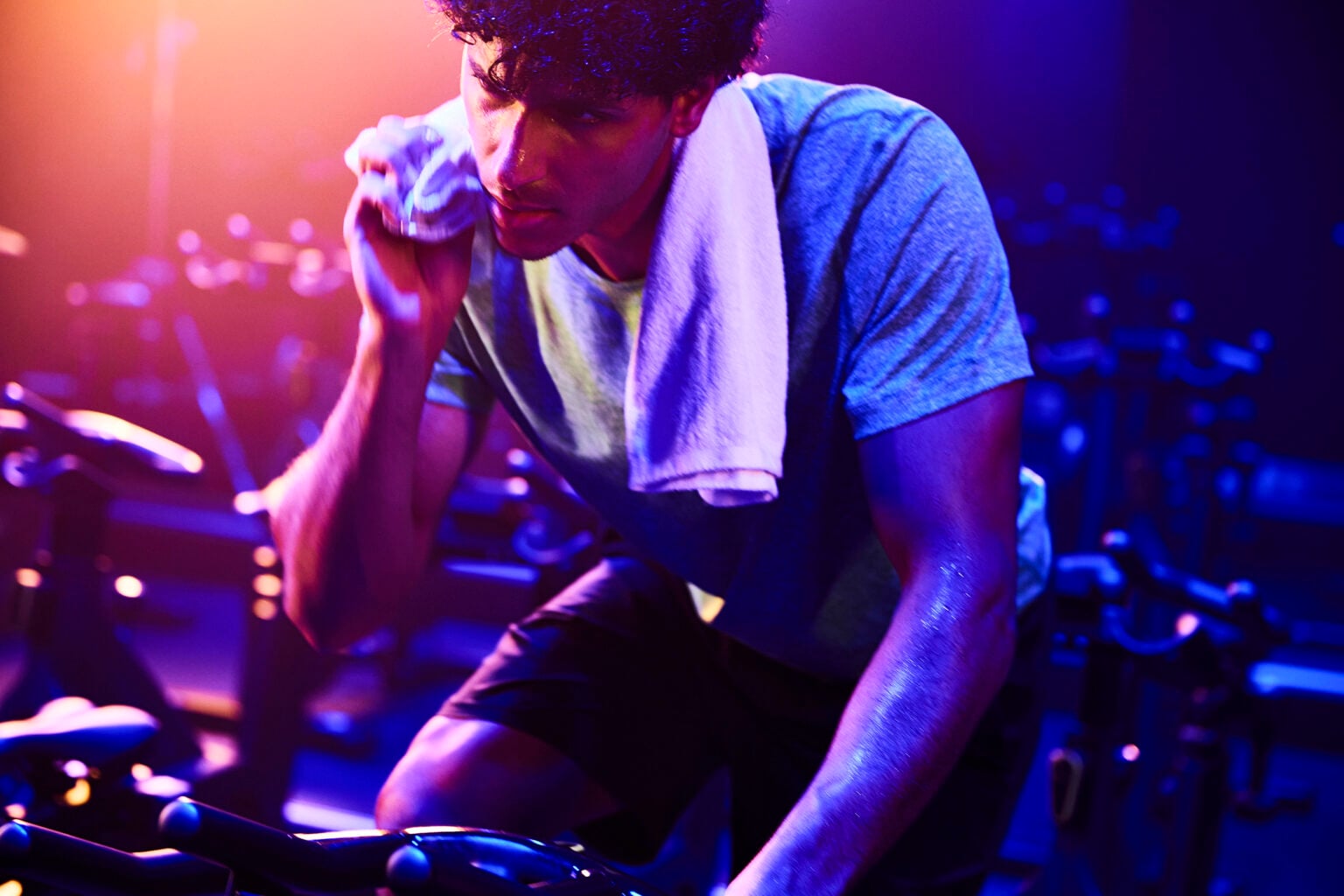 Man wiping his face with a towel during an indoor cycling class