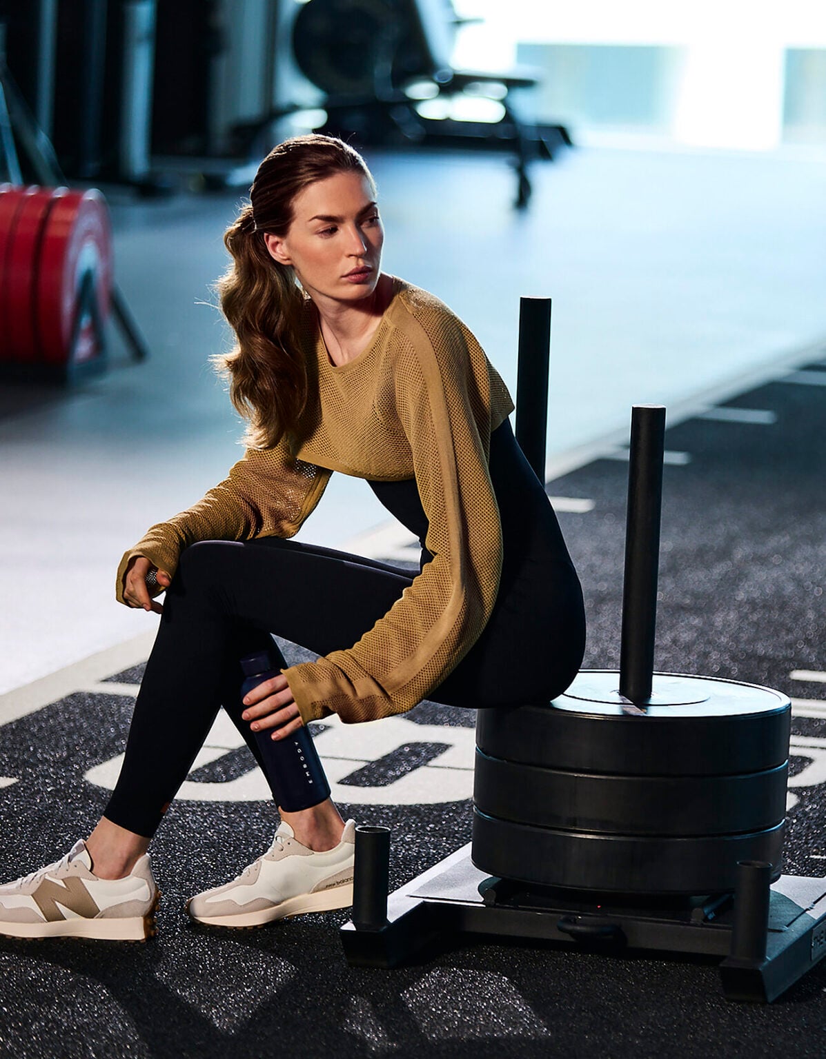 Woman resting on a weight sled on a gym floor