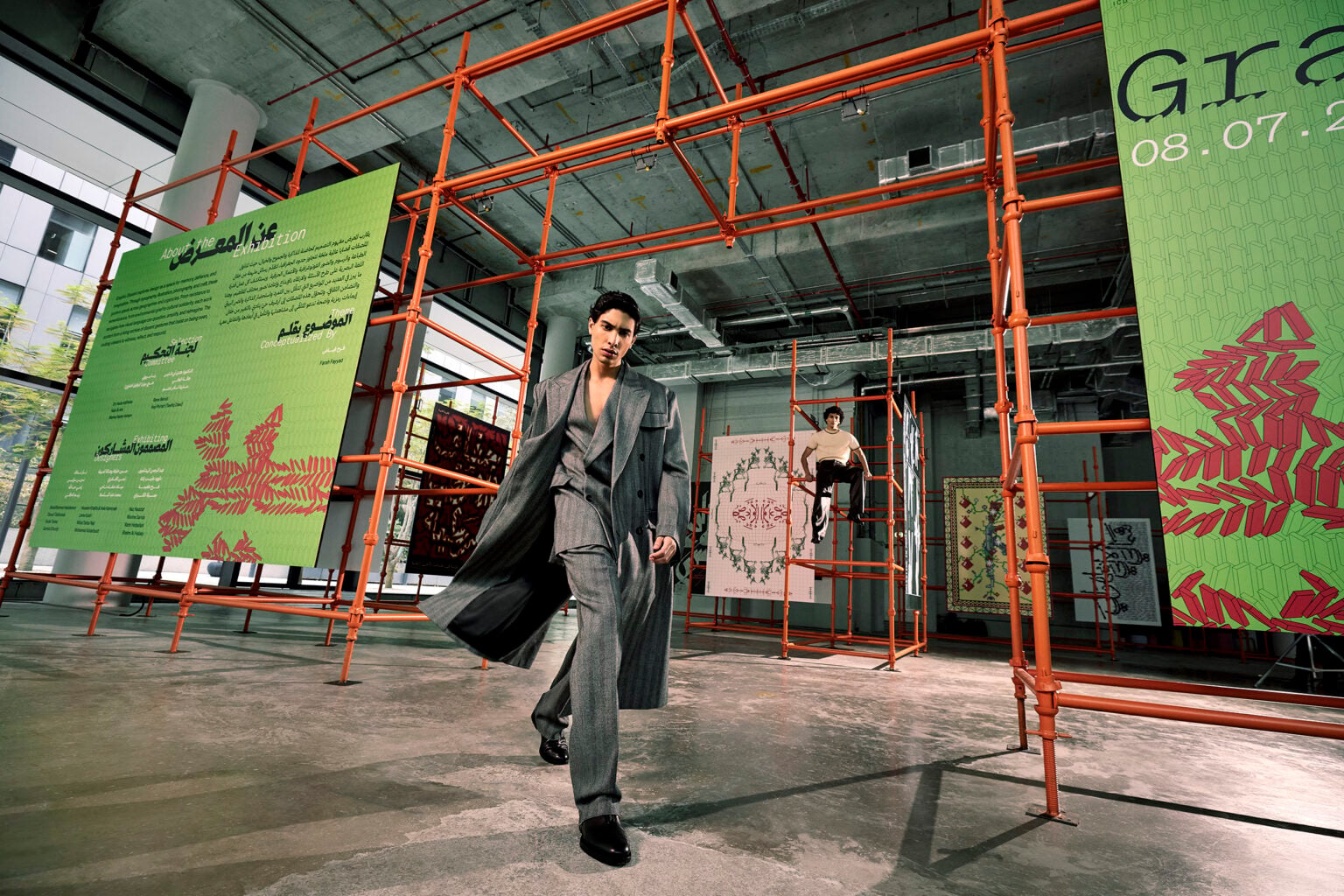 Man in a long coat walking through an art exhibition on orange scaffolding