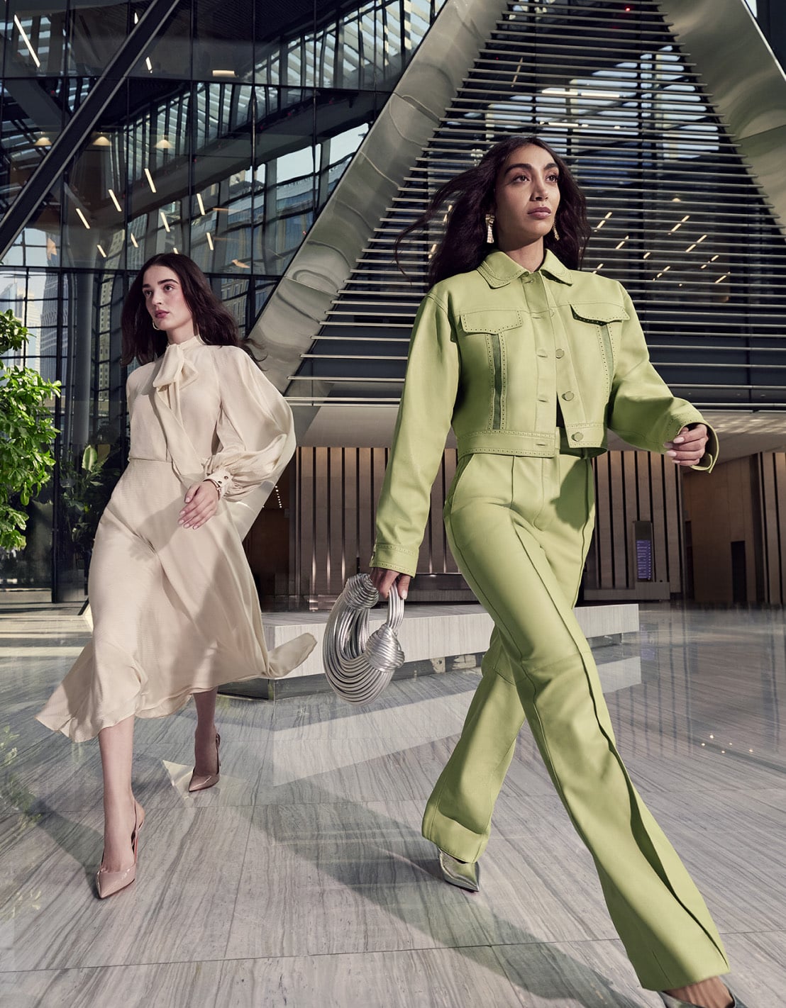 Two women in tailored outfits walking through the glass atrium at ICD Brookfield Place